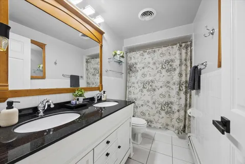 a bathroom with a double vanity sink toilet mirror and shower