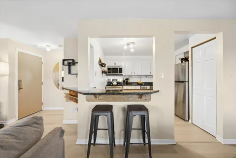 a kitchen with stainless steel appliances granite countertop a dining table chairs refrigerator and sink