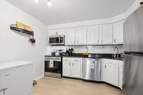 a kitchen with granite countertop white cabinets and white appliances