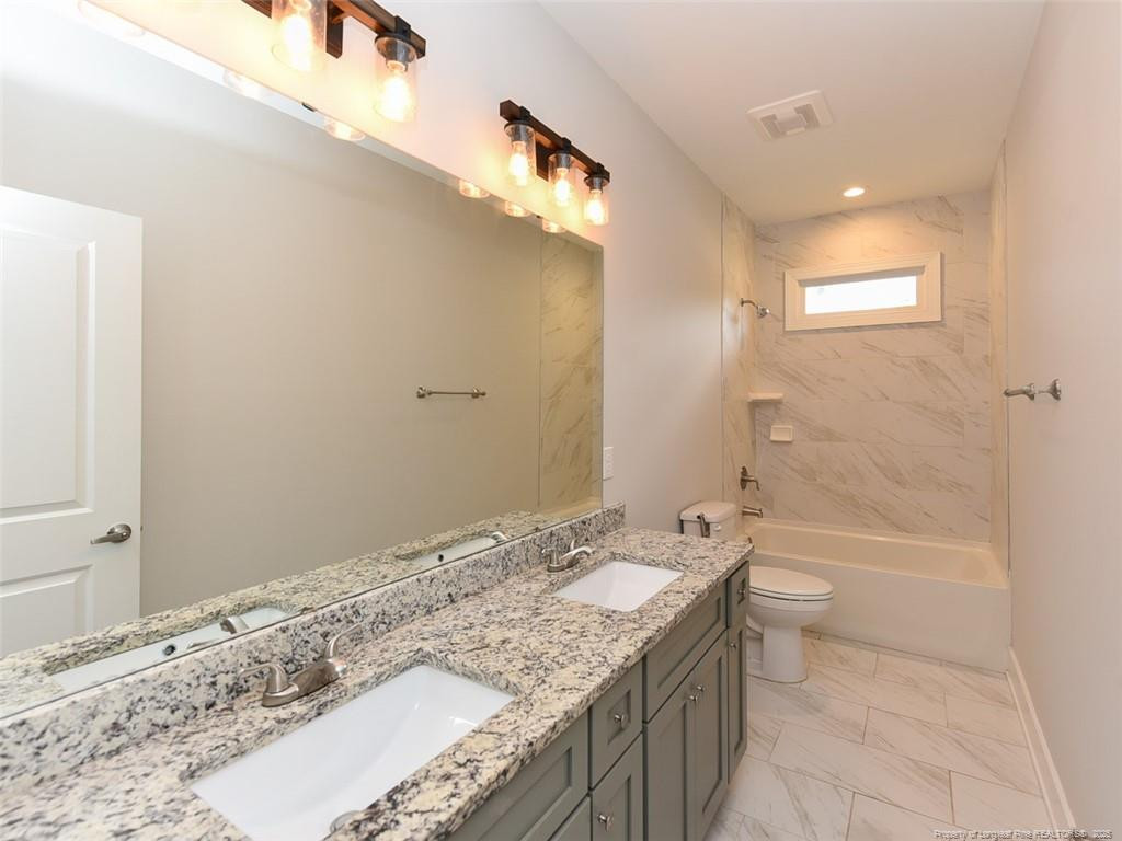 723 Lindley Drive Durham, NC 27703 - Photo 24 of 37 a bathroom with a granite countertop sink a toilet and bathtub