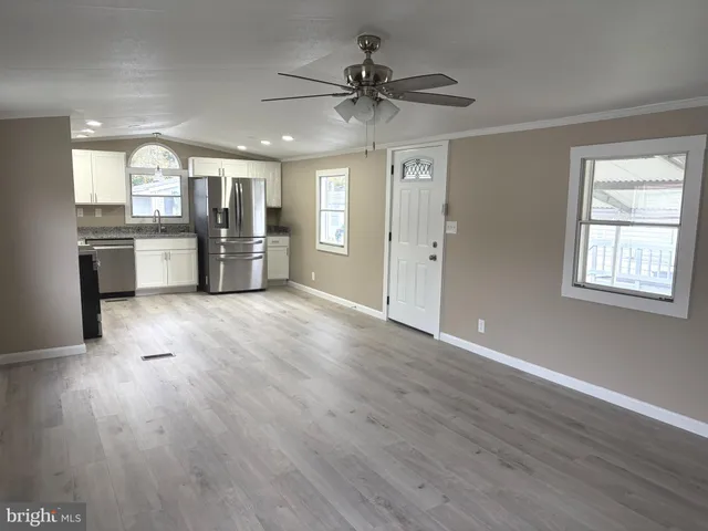a view of an empty room with window and wooden floor