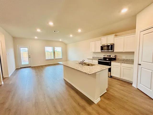 a kitchen with kitchen island granite countertop a sink cabinets and wooden floor