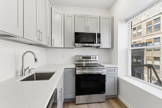 a kitchen with stainless steel appliances granite countertop a stove a sink and a microwave