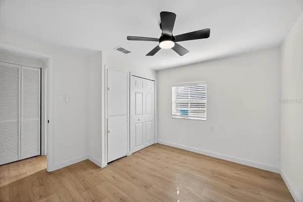 a view of empty room with wooden floor and ceiling fan