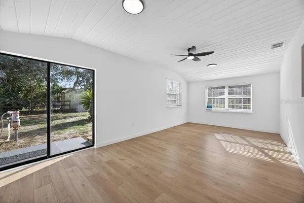 an empty room with windows and ceiling fan