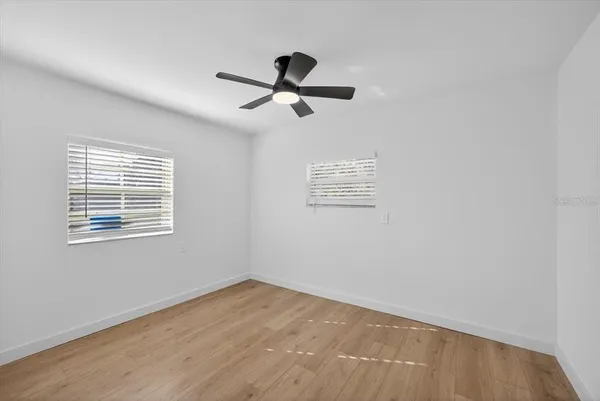 a view of empty room with wooden floor and fan