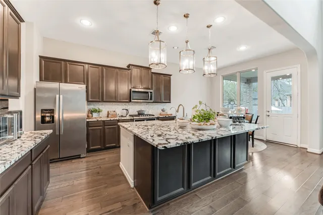 a kitchen with granite countertop kitchen island stainless steel appliances a sink stove and refrigerator