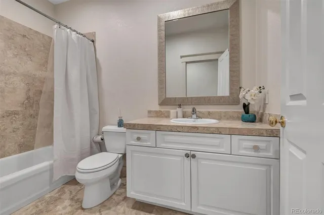 a bathroom with a granite countertop sink a toilet and a bathtub