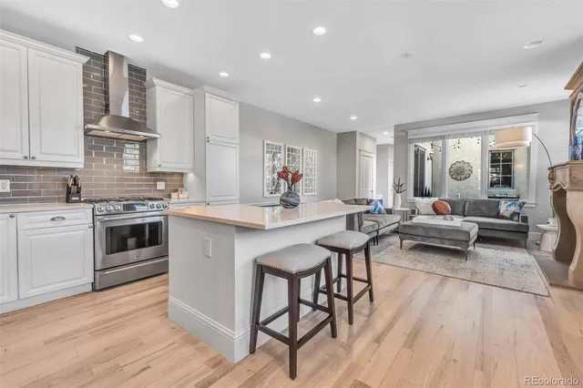 a kitchen with stainless steel appliances a white stove top oven a dining table and chairs with wooden floor