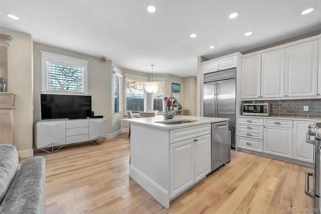 a large kitchen with kitchen island a sink white cabinets and stainless steel appliances