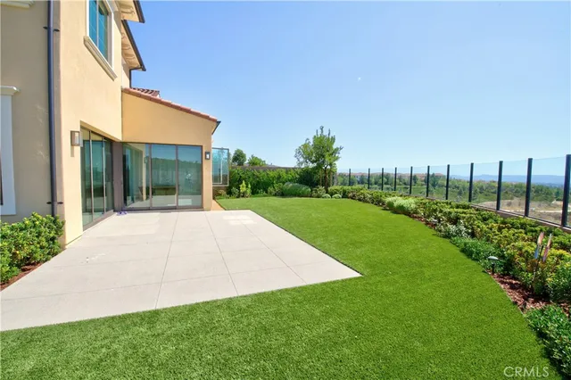 a view of yellow house with a big yard and potted plants