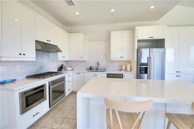 a kitchen with stainless steel appliances a stove a sink a refrigerator and white cabinets