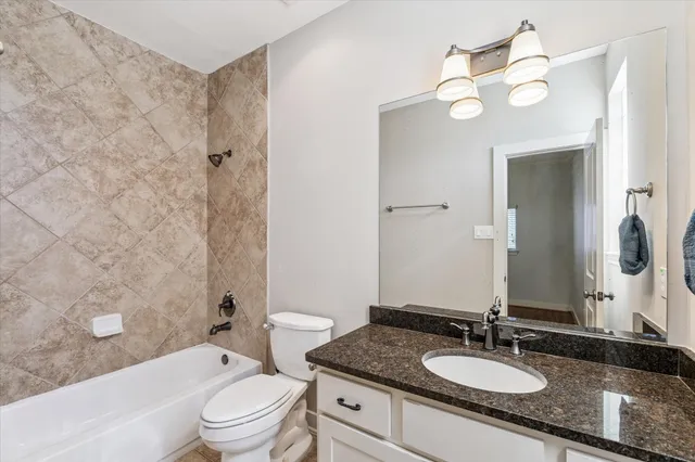 a bathroom with a granite countertop sink a toilet and a mirror