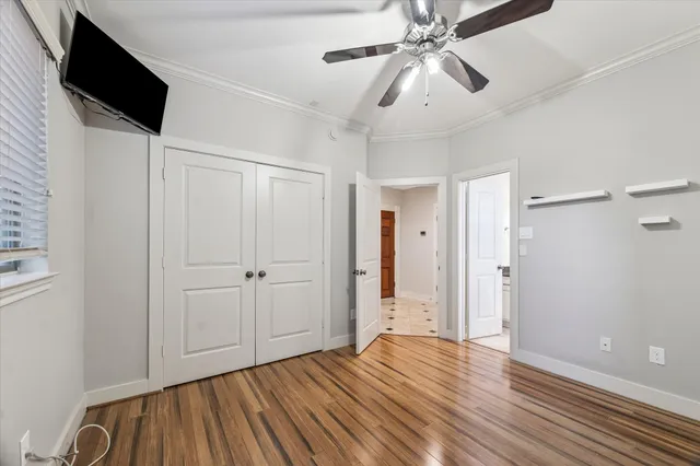 a view of empty room with wooden floor and fan