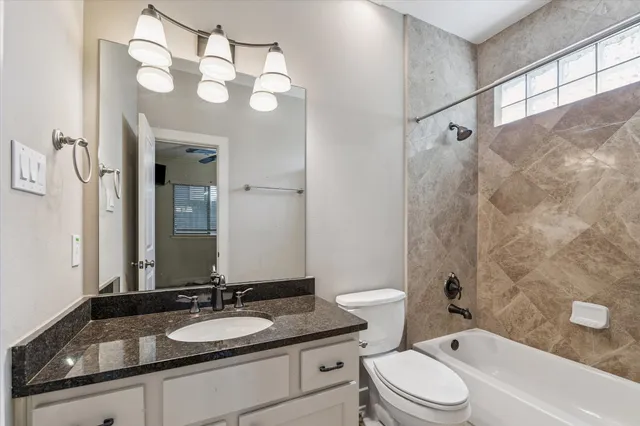 a bathroom with a granite countertop sink a toilet a mirror and shower