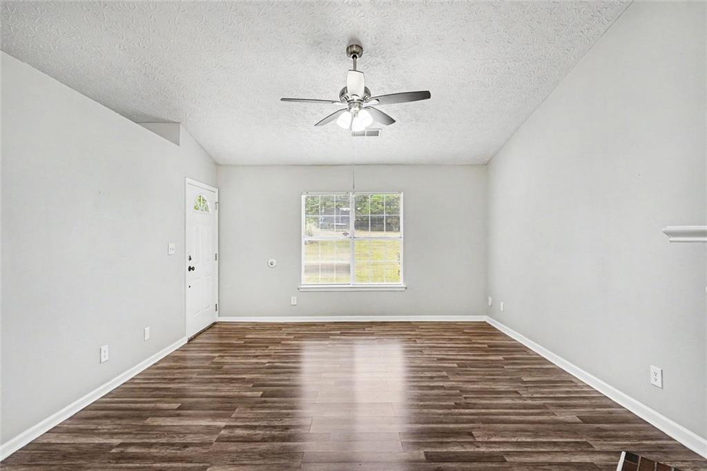 6221 Amberly Road Rex, GA 30273 - Photo 4 of 17 an empty room with wooden floor chandelier fan and windows