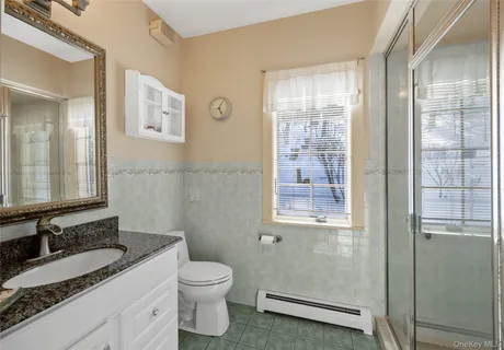 a bathroom with a granite countertop toilet a sink and a mirror