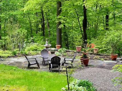 a view of a patio with table and chairs potted plants and large tree