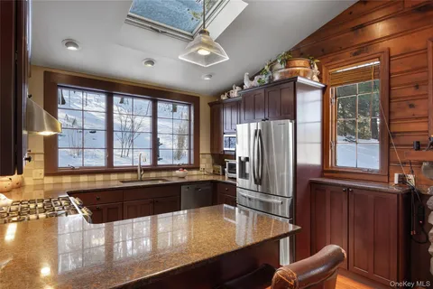 a kitchen with stainless steel appliances granite countertop a refrigerator a stove and a sink with wooden cabinets