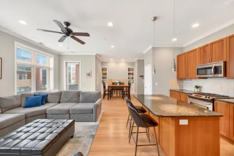 a living room with stainless steel appliances furniture a rug and a view of kitchen