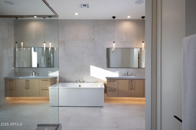 a bathroom with a double vanity sink mirror and bathtub