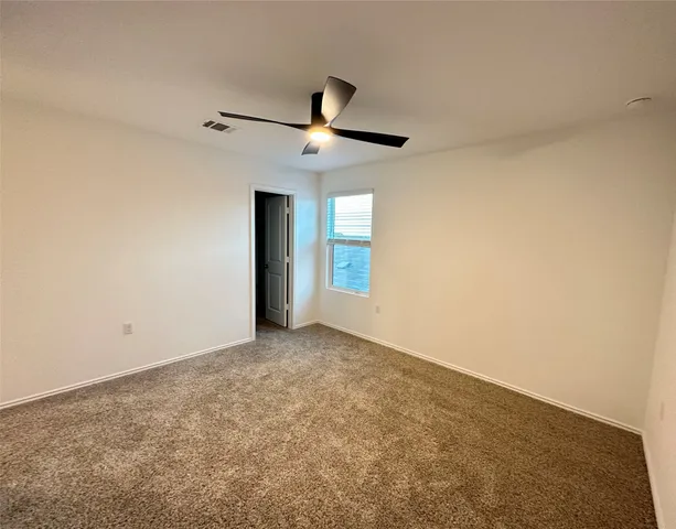 en empty room with ceiling fan and window