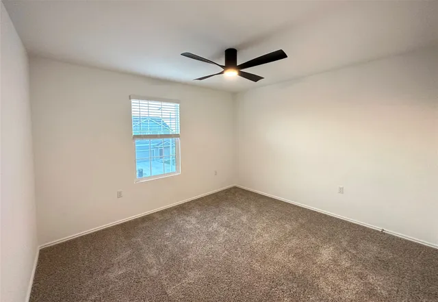 an empty room with a window and a ceiling fan