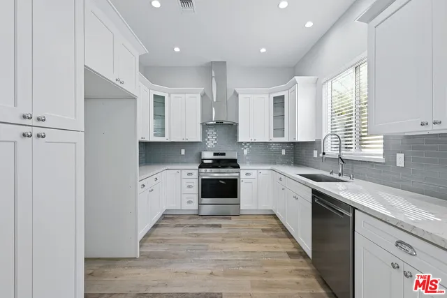 a large kitchen with stainless steel appliances granite countertop a stove a sink and white cabinets