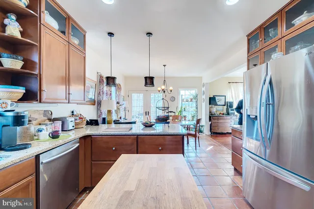 a large kitchen with stainless steel appliances a refrigerator a sink dishwasher a stove and a dining table with wooden floor