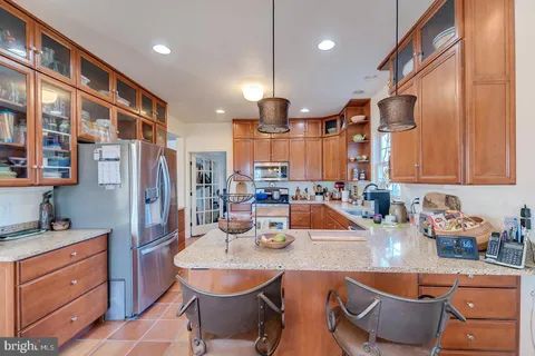 a large kitchen with stainless steel appliances a refrigerator a sink dishwasher a stove and a dining table with wooden floor