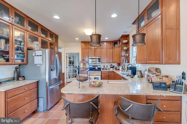 a large kitchen with stainless steel appliances a refrigerator a sink dishwasher a stove and a dining table with wooden floor