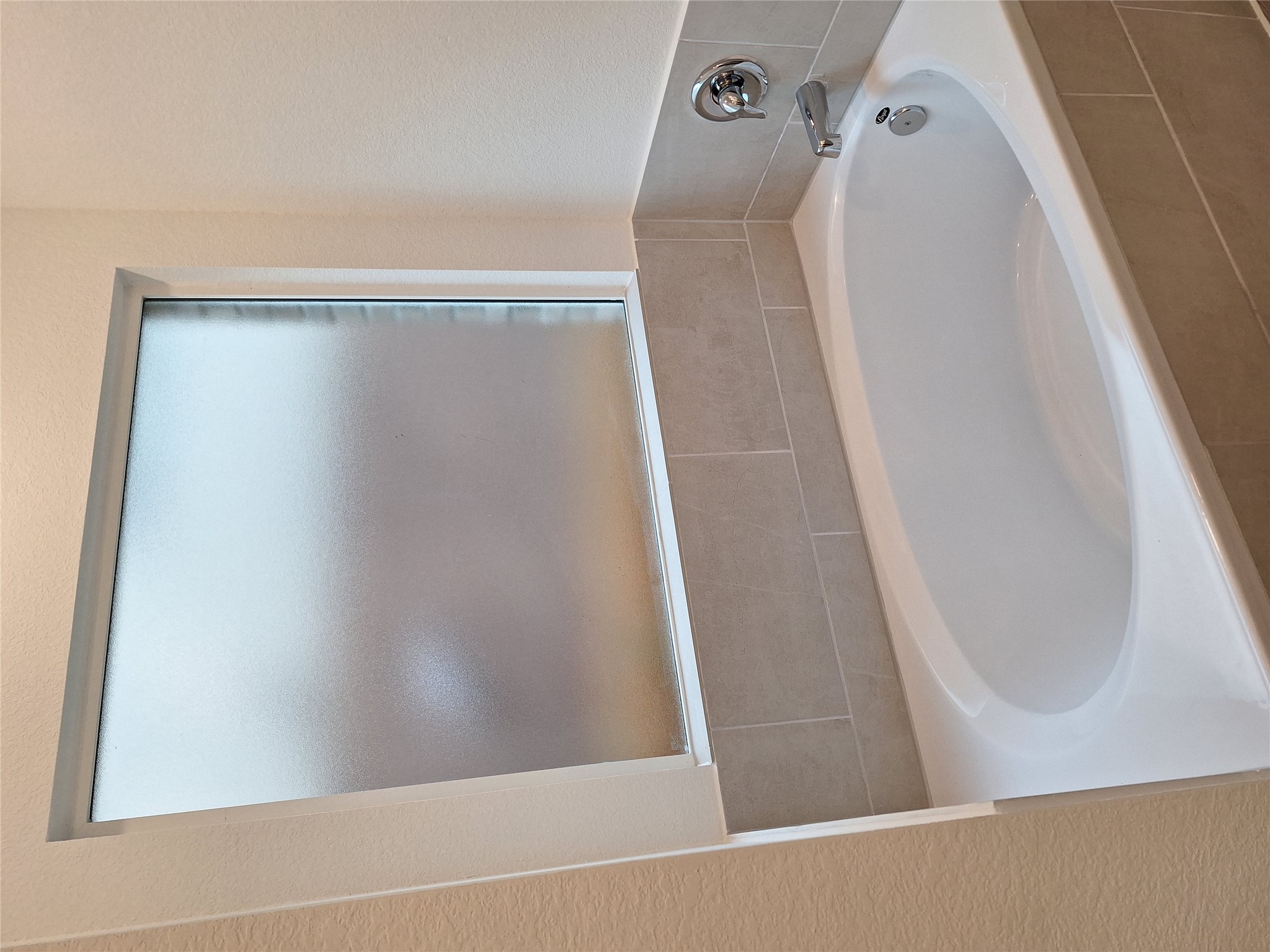 18001 Prairie Falcon Way Pflugerville, TX 78660 - Photo 28 of 38 Soaking tub with a tiled surround, chrome fixtures, and a frosted privacy window