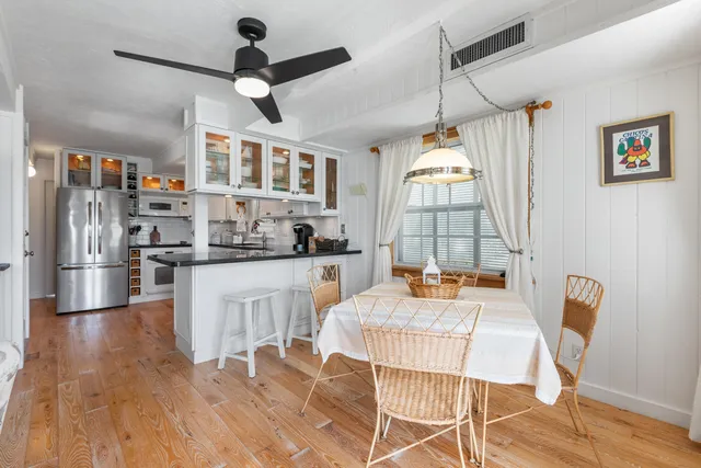 a kitchen with stainless steel appliances granite countertop a stove a refrigerator a dining table and chairs with wooden floor