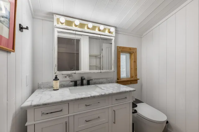 a bathroom with a granite countertop toilet sink and mirror