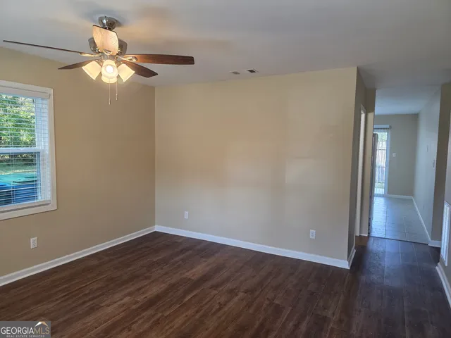 a view of an empty room with wooden floor and a window