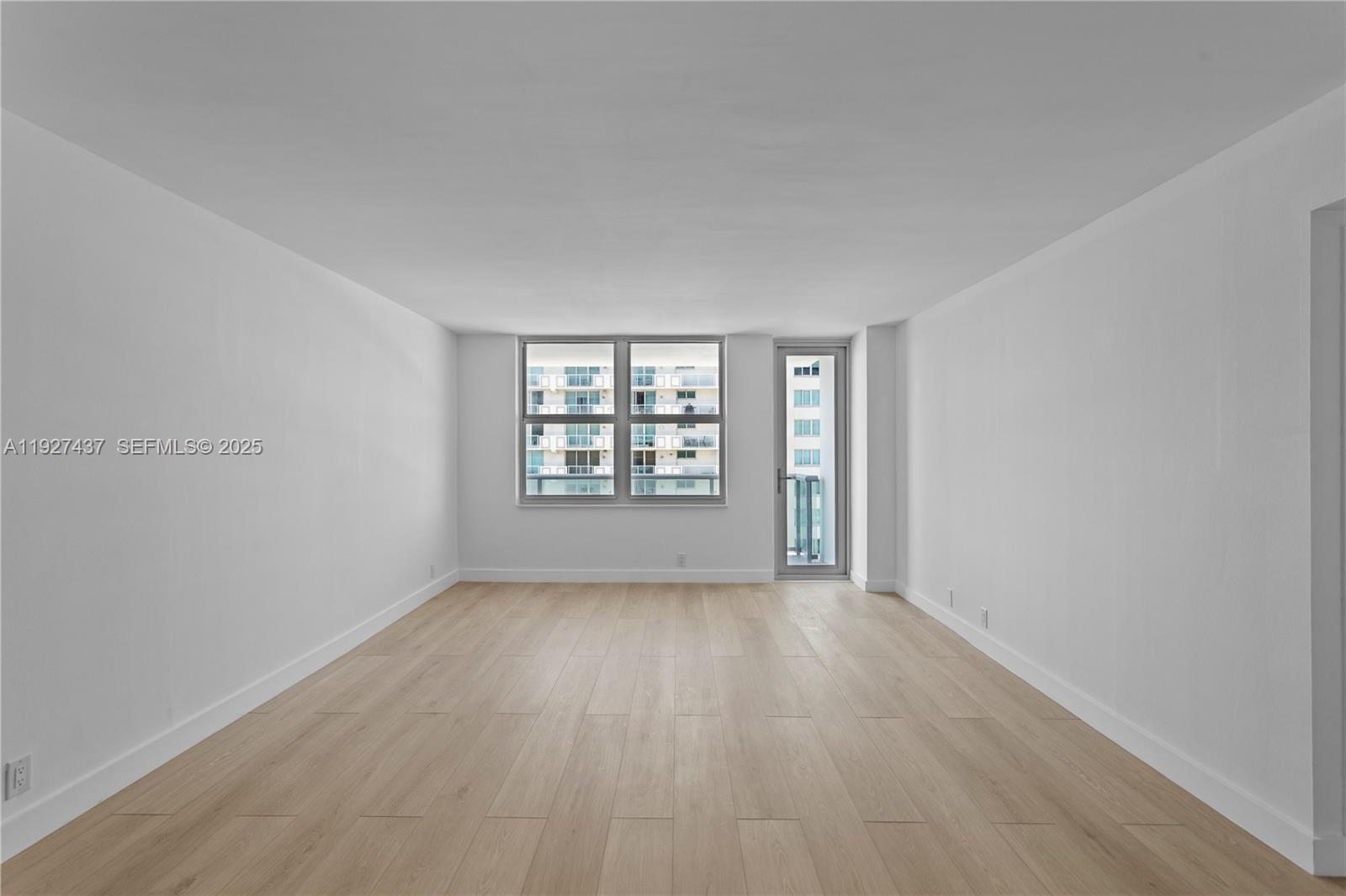 9511 Collins Avenue, Unit 806 Surfside, FL 33154 - Photo 12 of 32 an empty room with wooden floor and windows