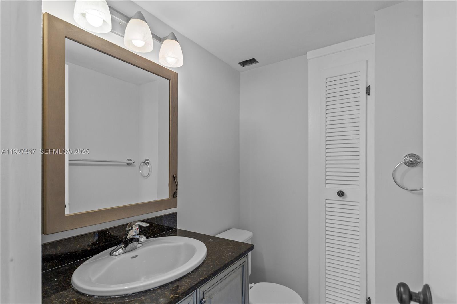 9511 Collins Avenue, Unit 806 Surfside, FL 33154 - Photo 17 of 32 a bathroom with a sink a toilet and mirror
