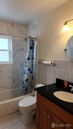 a bathroom with a granite countertop bathtub sink vanity mirror and toilet