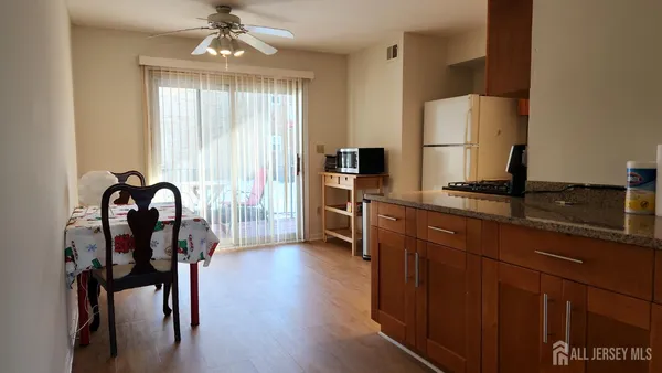 a kitchen with stainless steel appliances granite countertop a stove a refrigerator a sink dishwasher a dining table and chairs with wooden floor