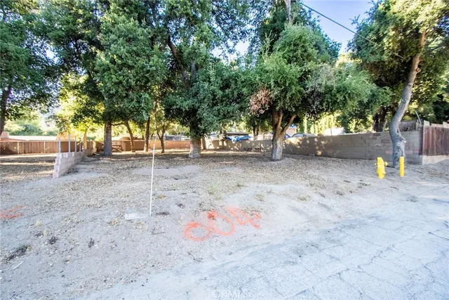 a backyard of a house with large trees and a wooden fence