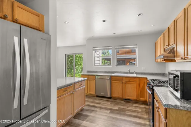 a kitchen with stainless steel appliances granite countertop a refrigerator a sink and a stove