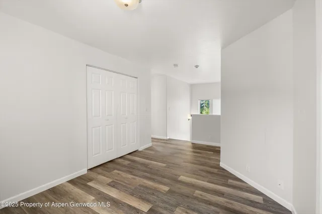 a view of a hallway with wooden floor and a kitchen