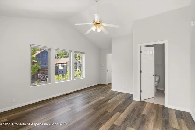 an empty room with wooden floor fan and windows