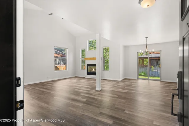a view of an empty room with a kitchen and fireplace