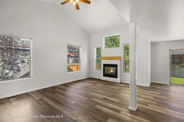 an empty room with wooden floor cabinet and windows