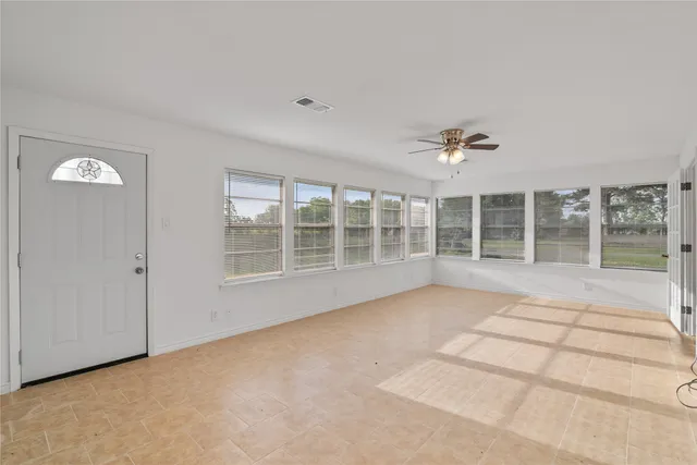 a view of an empty room with wooden floor and windows