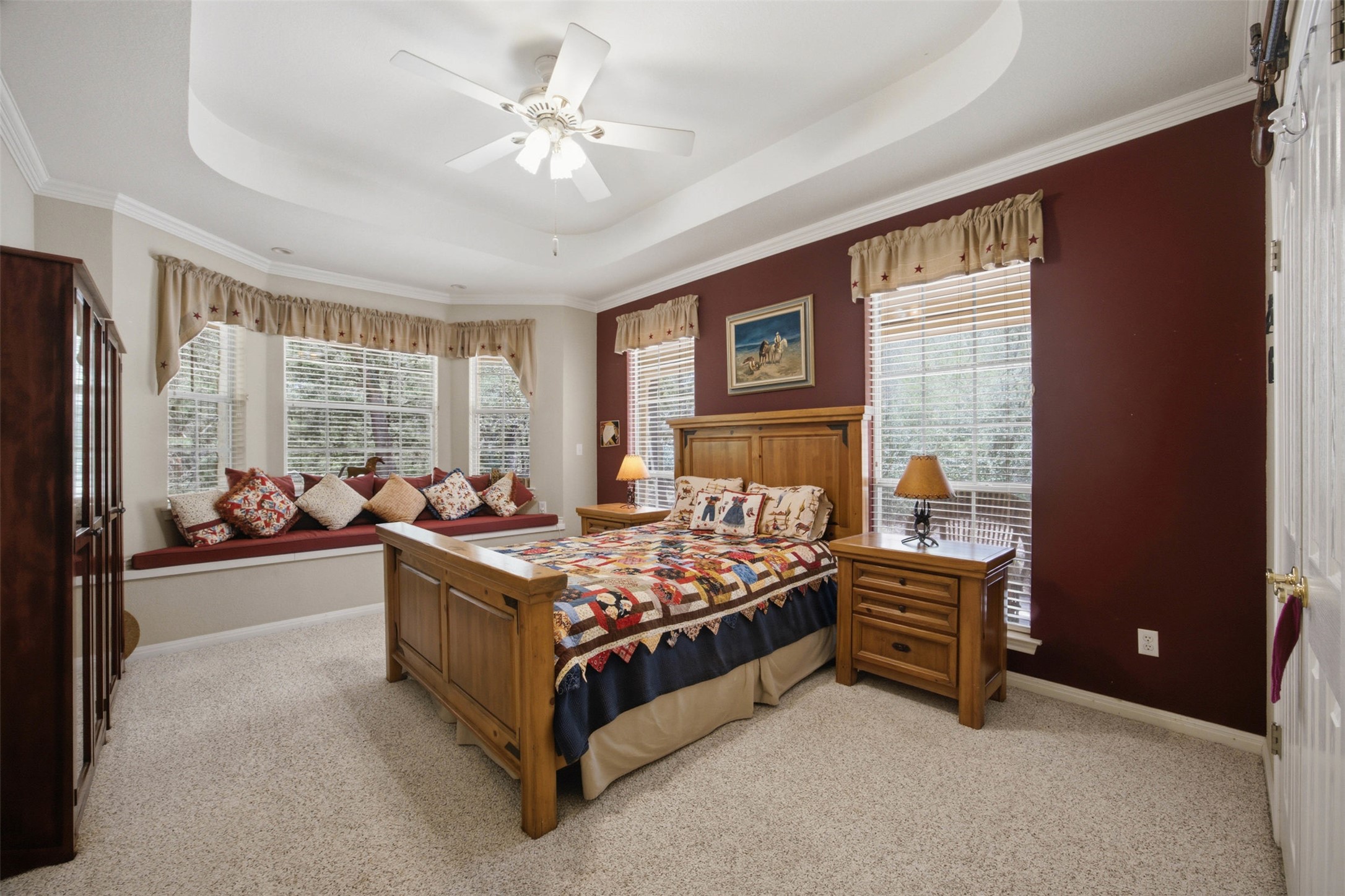 197 Elm Wood Drive Elgin, TX 78621 - Photo 19 of 37 A spacious bedroom offers a cozy window seat, crown molding, and a tray ceiling with a ceiling fan.