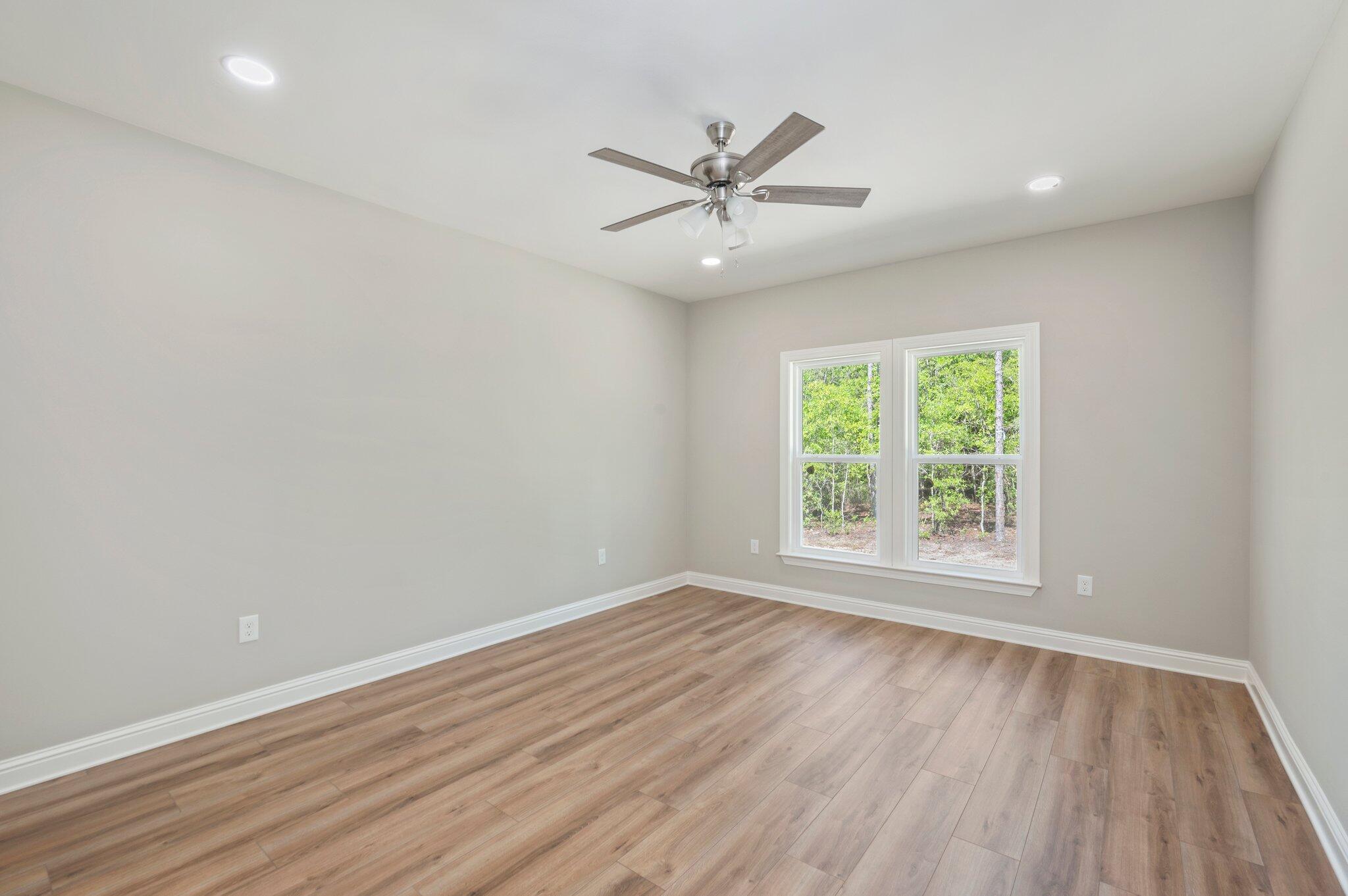 6043 Sand Hill Road Crestview, FL 32539 - Photo 17 of 36 an empty room with wooden floor fan and windows