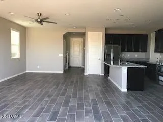an empty room with wooden floor and a kitchen
