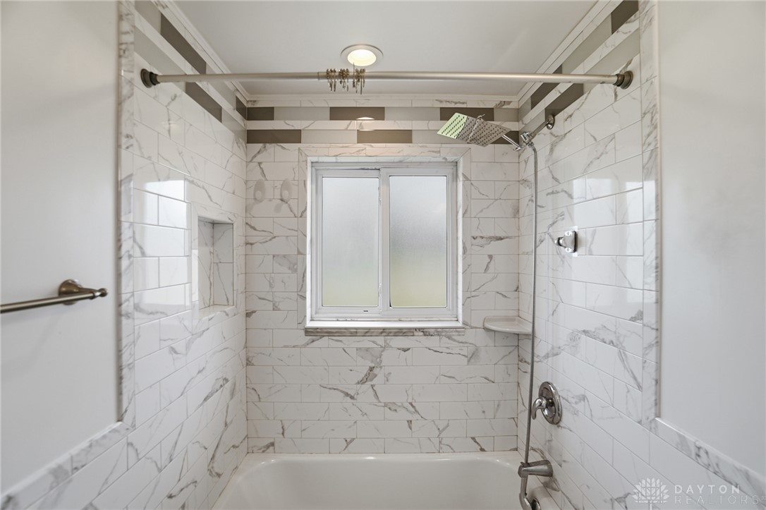 629 Storms Road Dayton, OH 45429 - Photo 36 of 51 This sleek bathroom features a modern shower-tub combination with elegant tiling and a window for natural light.